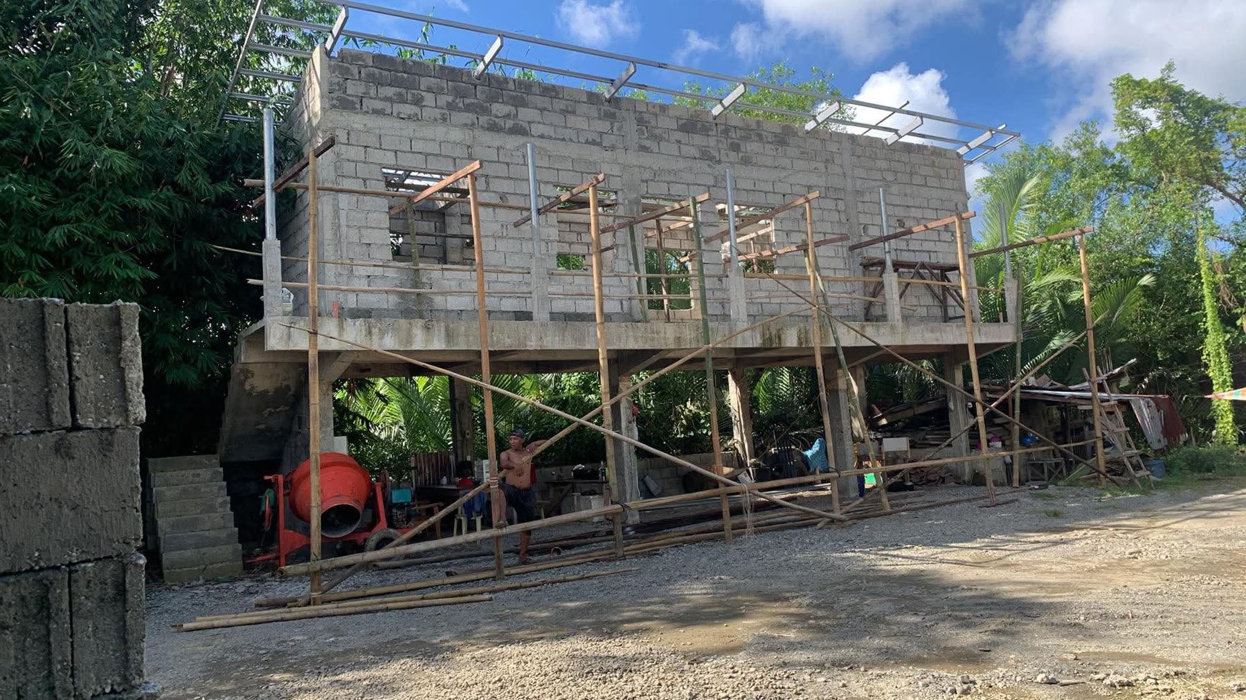 Blockwork walls at full height with timber shoring across the openings and blocks stacked on the ground